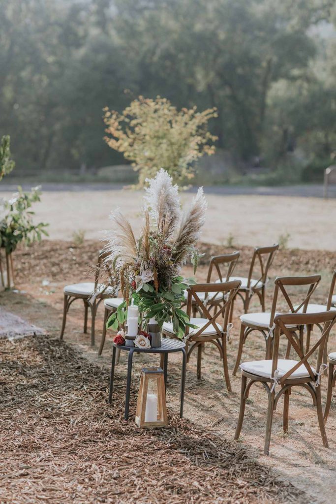 Photo of cross back chairs with cushions at rustic outdoor wedding ceremony site.