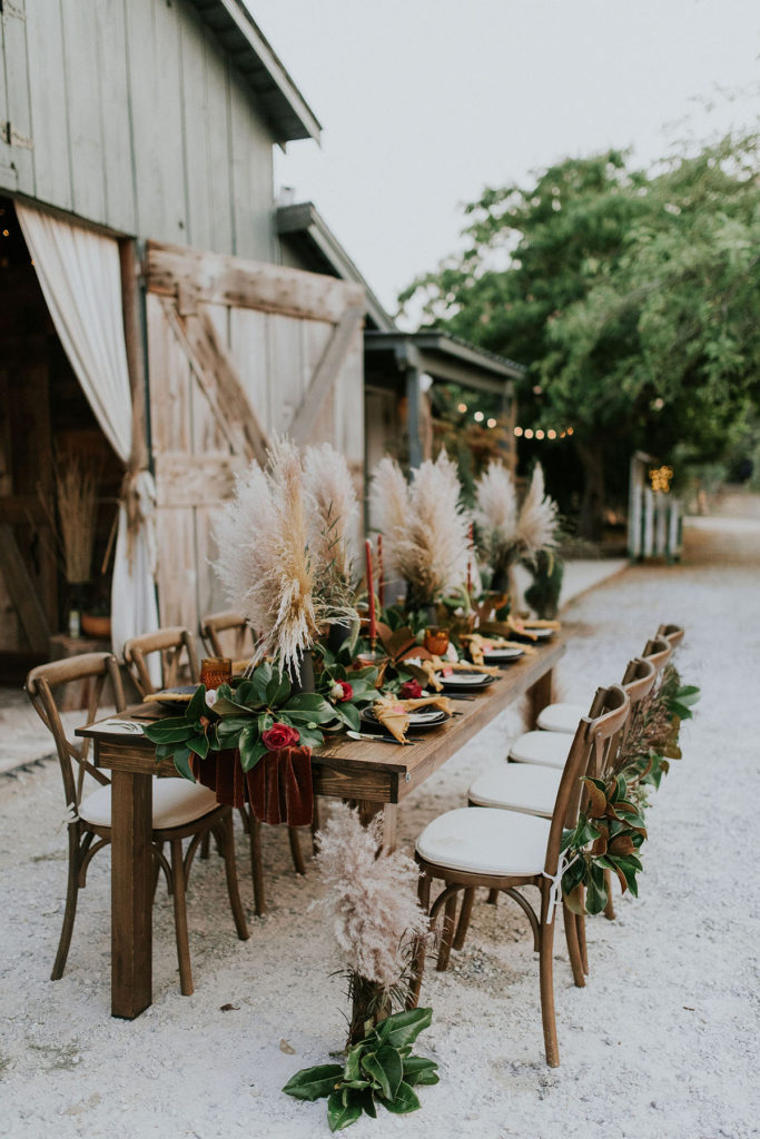 Photo of farmhouse table and cross back chairs at outdoor wedding.