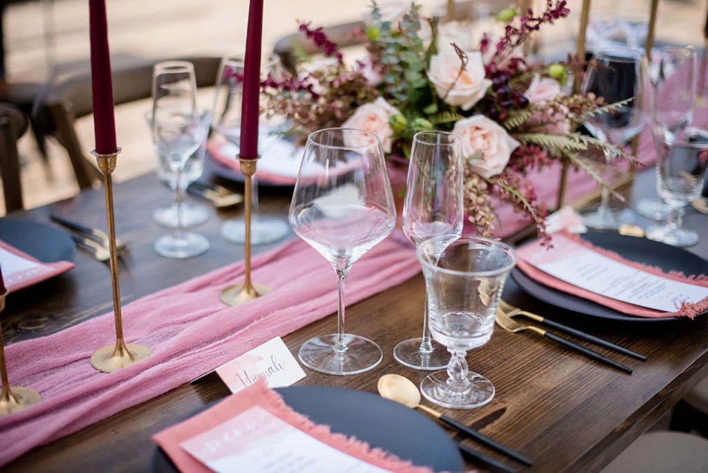 Table setting with flowers, matte black plates and clear glassware.