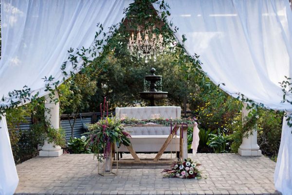 Creme color settee and farmhouse style sweetheart table with flowers.