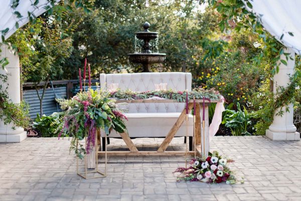 Creme color settee and farmhouse style sweetheart table with flowers.